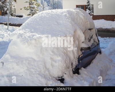 Ein Auto mit einer großen Schneeschicht übersät steht Auf der Straße Stockfoto