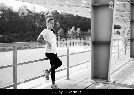 Sportliche Frau in aktiver Sportbekleidung, die im Stadion Pause einlegen Stockfoto