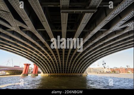 Unter der Blackfriars Railway Bridge und dem Bahnhof in London, Großbritannien. Die starken Stahlträger mit Nieten unter der Brücke halten die Struktur an ihrem Platz. Stockfoto