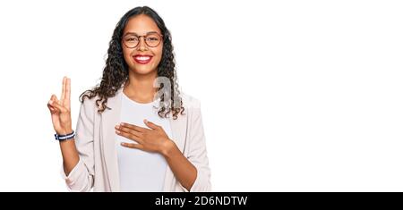 Junge afroamerikanische Mädchen in Business-Kleidung lächelnd Fluchen mit der Hand auf der Brust und die Finger nach oben, so dass eine Treue Versprechen Eid Stockfoto