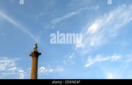 Nelson's Column in Trafalgar Square, London, UK - eine historische und touristische Sehenswürdigkeit im Zentrum von London. Spitze der Nelsons Säule gegen blauen Himmel und Wolken Stockfoto