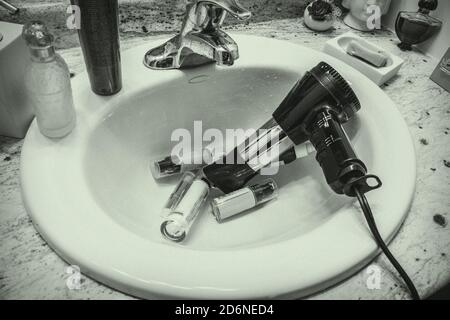 Der Haartrockner fiel herunter oder wurde versehentlich oder abgelenkt im Waschbecken gelassen. Stockfoto