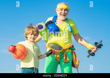 Sport für Kinder. Vater und Sohn sportlich - Familie Zeit zusammen. Älterer Mann und niedlicher kleiner Junge, der auf blauem Himmel Hintergrund trainiert - isoliert. Stockfoto