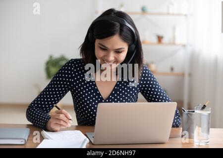 Lächelnd asiatische Mädchen in Kopfhörer Studie entfernt auf Laptop Stockfoto