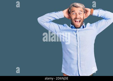 Junge schöne blonde Mann trägt elegante Hemd verrückt und mit Händen auf dem Kopf Angst, Angst und überrascht von Schock mit offenem Mund Stockfoto