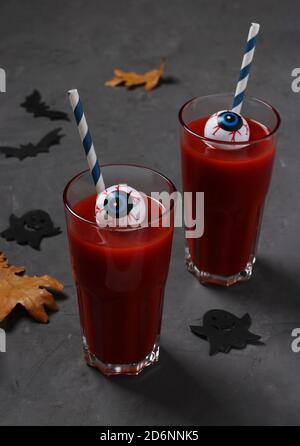 Augen im Glas mit Tomatencocktail auf dunklem Tisch für Herbstferien Halloween. Nahaufnahme. Stockfoto