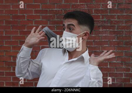 Porträt eines jungen Mannes mit einer medizinischen Maske Überrascht vor einer Mauer Stockfoto