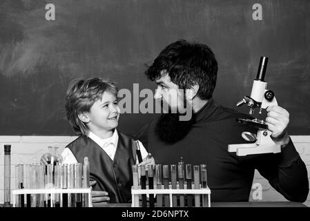 Lehrer hilft kleinen Jungen mit Lektion. Fröhlich lächelnder kleiner Junge und Lehrer, der Spaß an der blauen Wand hat. Elternschaft. Zurück zur Schule. Stockfoto