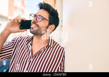 Junge gutaussehende hispanischen Mann mit Bart lächeln glücklich im Freien sprechen Am Telefon Stockfoto