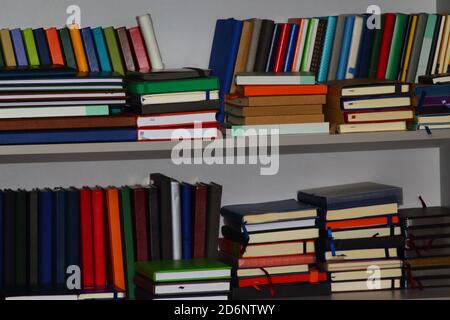 Stapel von verschiedenen Probe Leder gebundene Tagebücher oder Bücher in einem Graues Bücherregal Stockfoto