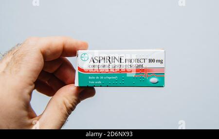 Paris, Frankreich - Mar 14, 2018: POV männliche Hand hält Pakcage von Aspirin schützen 100mg isoliert auf weißem Hintergrund Stockfoto