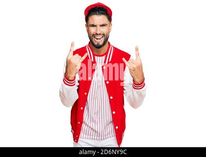 Junger Mann mit Bart tragen Baseball Uniform Schreien mit verrückten Ausdruck tun Rock-Symbol mit Händen nach oben. Musik-Star. Heavy-Konzept. Stockfoto