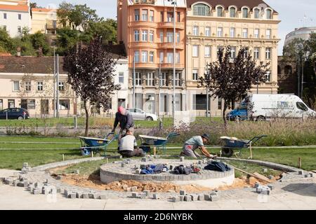 Belgrad, Serbien - 09. Oktober 2020: Bauarbeiter, die den Granit Pflastersteinbau arrangieren, dekorativen Fußgängerweg und Sockel in der Stockfoto