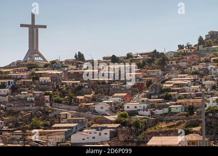 Coquimbo, Chile - 7. Dezember 2008: Nahaufnahme der hohen Millennium Cross Trinity, umgeben von Häusern in verschiedenen Farben unter einer blutigen Wolkenlandschaft. Stockfoto