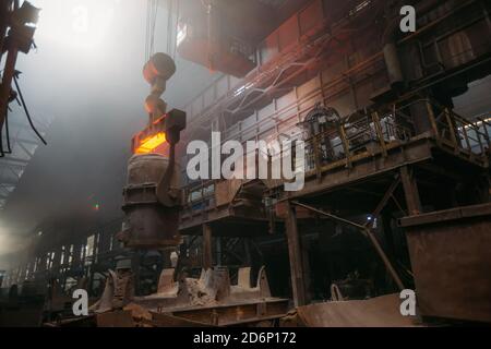 Eisenguss und die Gießerei. Deckenkran mit Schöpfkelle aus geschmolzenem Metall in der metallurgischen Fabrik Stockfoto