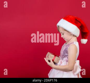 Niedliche liebenswert lächelnd Mädchen halten weihnachtsgeschenk isoliert auf rot Stockfoto