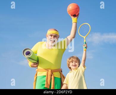 Großvater und Enkel mit Basketballball und Yogamatte in den Händen. Vater und Sohn beim Training. Alter ist keine Entschuldigung, um auf Ihre Gesundheit zu schlaffen. Wird Durchgeführt Stockfoto