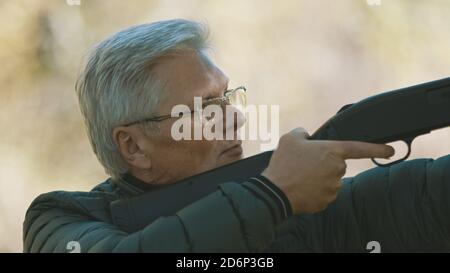 Älterer grauhaariger Mann, der eine Waffe in den Händen hält. Krieg oder Revolution Konzept. Hochwertige Fotos Stockfoto