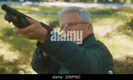 Älterer grauhaariger Mann, der eine Waffe in den Händen hält. Krieg oder Revolution Konzept. Hochwertige Fotos Stockfoto