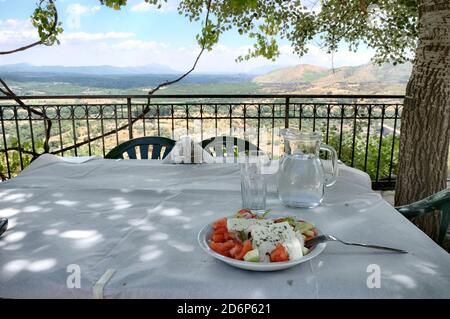 Klassischer griechischer Salat auf dem Tisch unter dem Schatten eines Baum Stockfoto