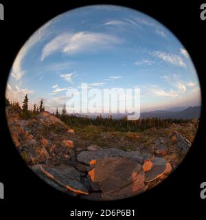 Rauchschichten aus einem nahegelegenen Waldfeuer geben eine Orange Glühen, um die untergehende Sonne über den Cascade Mountains AS Von der Spitze des Red Blanket Mountain aus gesehen Stockfoto