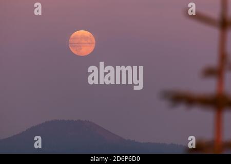 Ein Vollmond geht im Osten wie die Sonne auf Setzt sich im Westen mit dicken Schichten von Rauch Von einem in der Nähe gelegenen Waldbrand in den Cascade Mountains schaffen ein Stockfoto