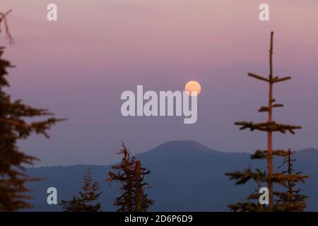 Ein Vollmond geht im Osten wie die Sonne auf Setzt sich im Westen mit dicken Schichten von Rauch Von einem in der Nähe gelegenen Waldbrand in den Cascade Mountains schaffen ein Stockfoto