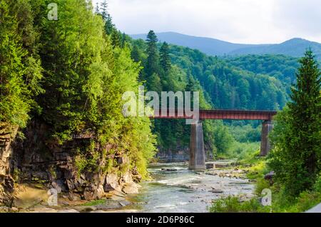 Malerischer Ort, ein Gebirgsfluss mit einer schnellen Strömung von Felsen und einer Brücke Stockfoto