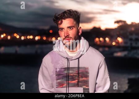 Junger Kaukasier, der an einem Seehafen posiert. Stockfoto