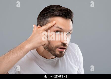 Mann mittleren Alters auf der Suche nach Falten auf seinem Gesicht Stockfoto