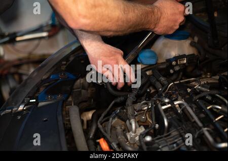 Leitender Mechaniker, der am Motorraum arbeitet und ein Ölleck repariert In der heimischen Garage Stockfoto