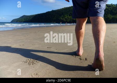 Mann beim Spaziergang am Strand von Etty Bay, in der Nähe von Innisfail, Queensland, Australien. Nein, MR Stockfoto