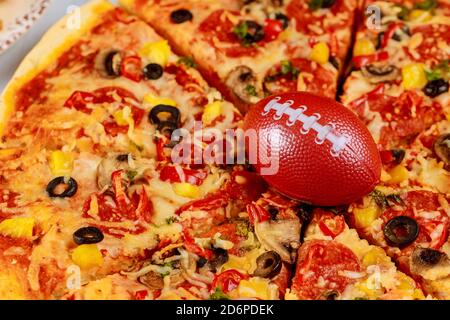 Pepperoni Supreme Pizza mit Fußball für american Football Party. Stockfoto