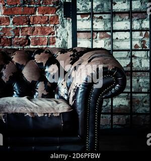 Altes Vintage-Sofa auf dem Hintergrund der Ziegelwand und Gitter, selektiver Fokus Stockfoto