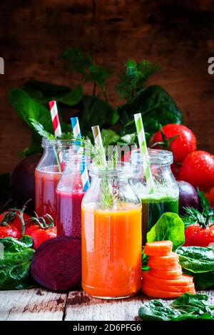 Gesunde Gemüse-Smoothie-Glasflaschen mit Strohhalmen, Vintage-Holzhintergrund, selektiver Fokus Stockfoto