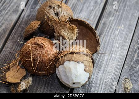 Frische Kokosnüsse auf Holzuntergrund mit Kokosmilch in kleinen Gläsern gebrochen Stockfoto