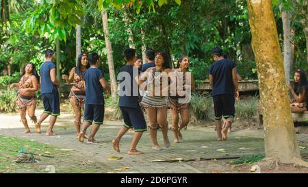 Tena, Napo / Ecuador - Oktober 10 2020: Gruppe von Jugendlichen, die mit typischen Kostümen der ethnischen Gruppen des ecuadorianischen Amazonas in einem Park tanzen Stockfoto