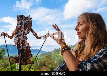 Frau hält in der Hand alte traditionelle Schattenpuppe von Bali Insel - Wayang Kulit. Kultur, Religion, Kunst Festivals der balinesischen und indonesischen Menschen. Stockfoto