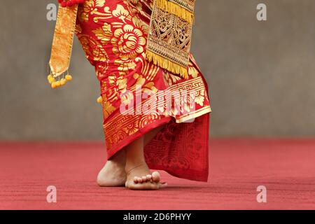 Asiatischer Hintergrund. Schöne balinesische Tänzerin Frau in traditionellen Sarong Kostüm tanzen Legong Tanz. Beinbewegungen. Kunst, Kultur Indonesiens Stockfoto