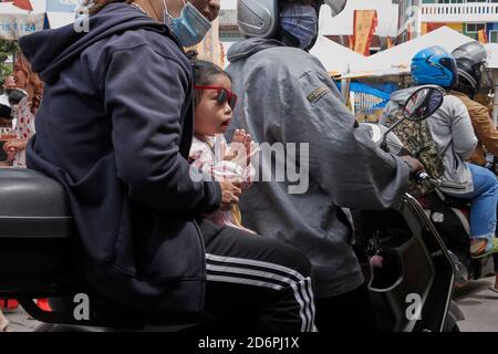 Thailandgrüße. Thailand Wai, Kind auf einem Motorrad mit ihren Eltern in einer traditionellen Grußgeste namens Wai die Hände umklammend, Stockfoto