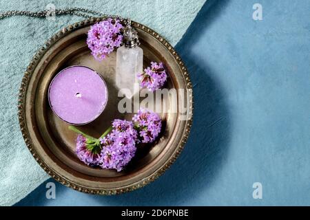 Heidnische Ritualobjekte. Ein Quarzcharm, eine Kerze und vervain Blumen, top shot mit Copyspace auf blauem Hintergrund Stockfoto