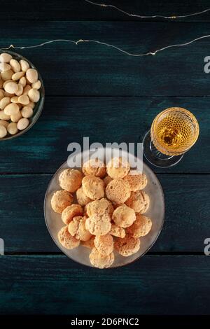 Amaretti, traditionelle italienische Mandelkekse, mit einem Glas Amaretto-Likör, über dem Kopf auf einem dunkelblauen Holzhintergrund geschossen Stockfoto