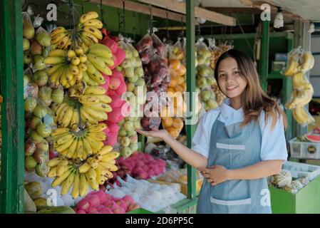 Lächelnde Frau Shop Assistentin steht neben Bio-Obst in Der Stand Stockfoto