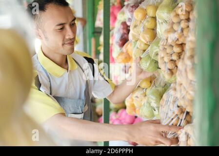 Asiatische junge Arbeiter verkaufen frisches Obst im Geschäft Stockfoto