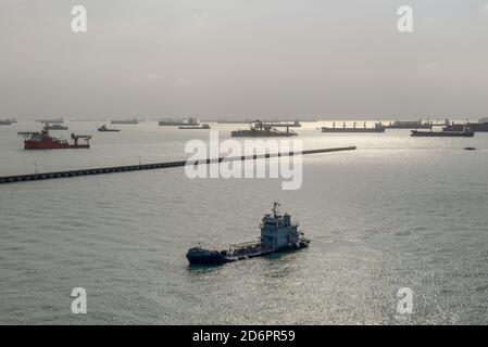 Singapur - 3. Dezember 2019: Große Sammlung von kommerziellen Frachtschiffen warten am Ankerplatz vor der Küste von Singapur im Hintergrund. Stockfoto