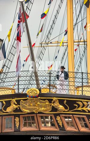 SS Großbritannien Heck Blick. Schauspieler in Kleid, der vor dem Geländer steht. Signalfahnen, Kleid Schiff Takelage. Bristol Dockyard. GB Farbenfrohe Gebäude. Stockfoto