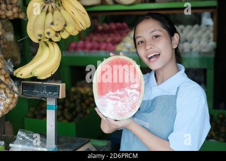 Eine halbe Wassermelone in der Hand einer Frau bringt Früchte verkäufer im Obstladen Stockfoto