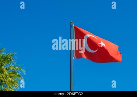 Die Flagge der Türkei erhebt sich und winkt dem Wind mit Himmel im Hintergrund zu. Schwenkende Nationalflagge der Türkei. Reisen, Tourismus. Stockfoto