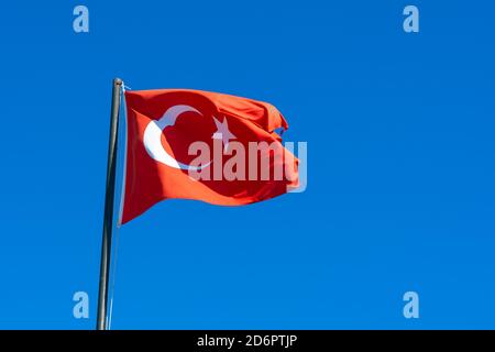 Symbol des türkischen Volkes. Schwenkende Nationalflagge der Türkei. Nationalflagge der Türkei weht im Wind gegen einen blauen Himmel. Stockfoto