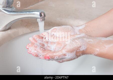 Hände mit Seife waschen. Nahaufnahme einer Frau, die sich im Badezimmer die Hände wäscht, um eine Virusinfektion zu verhindern. Empfohlene Reinigung mit Seife und fließendem Wasser Stockfoto